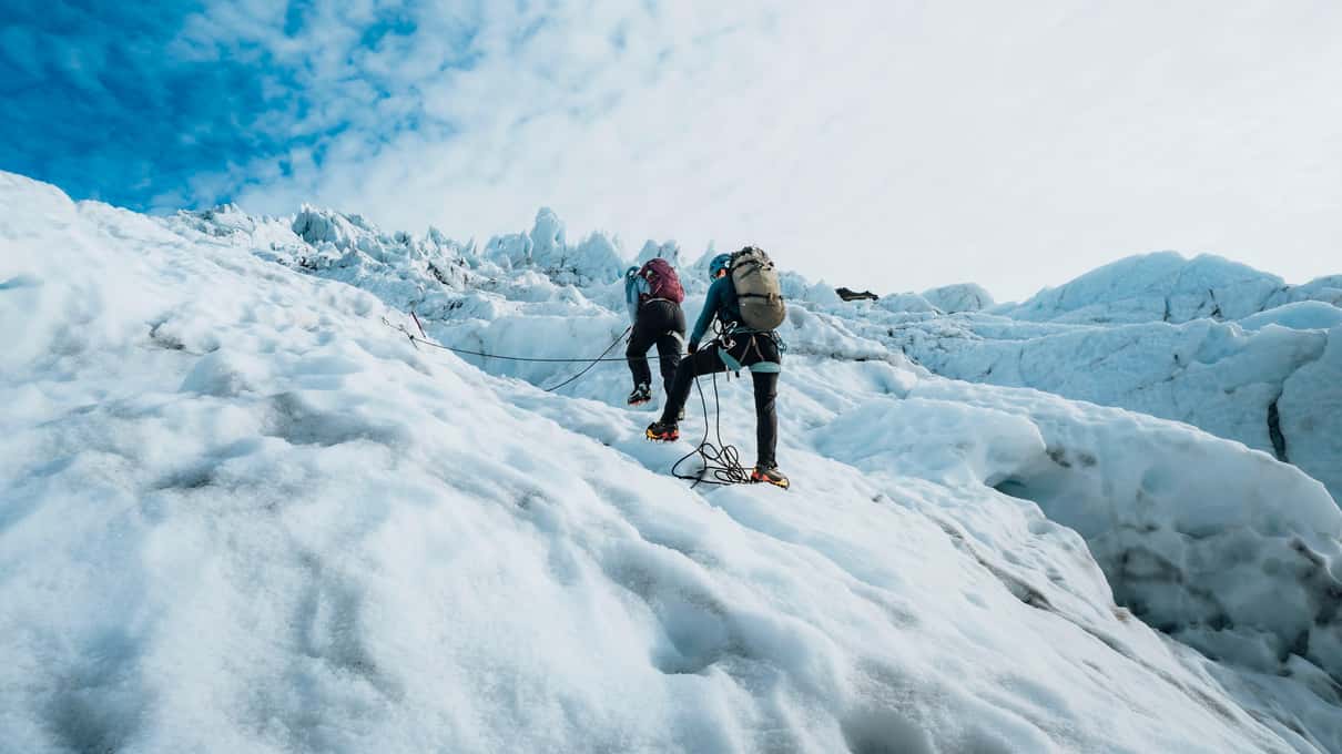 Two climbers with ropes and ice axes working their way up a steep crevassed face of ice on Vatnajökull