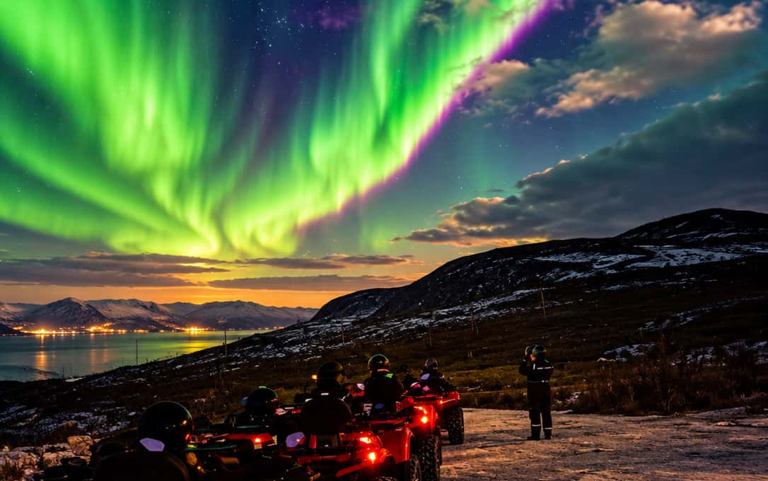 A bright green and pink aurora over a fjord with town lights along the shore