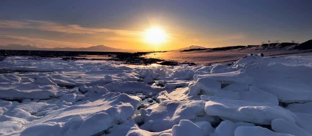 Low winter sun setting over snow-covered shore ice on the Okhotsk coast