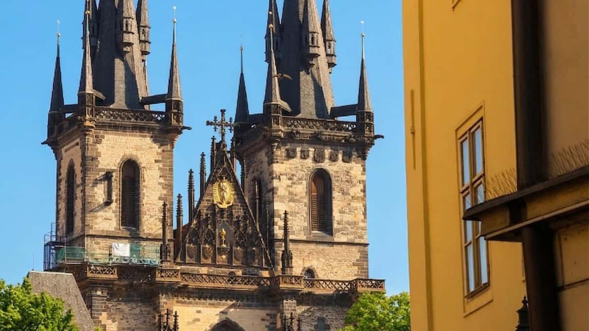 The two Gothic spires of the Týn Church in Prague's Old Town rising against a clear blue sky