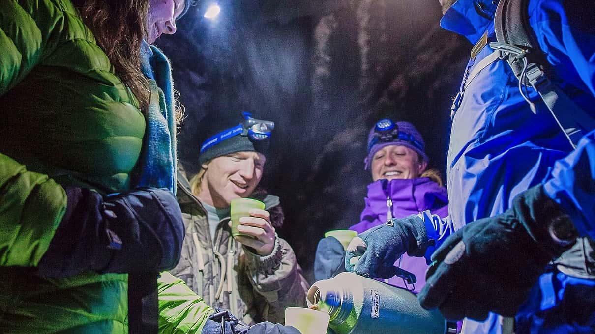 Gruppe vandrere med pandelamper deler kopper med varm chokolade i den mørke Johnston Canyon
