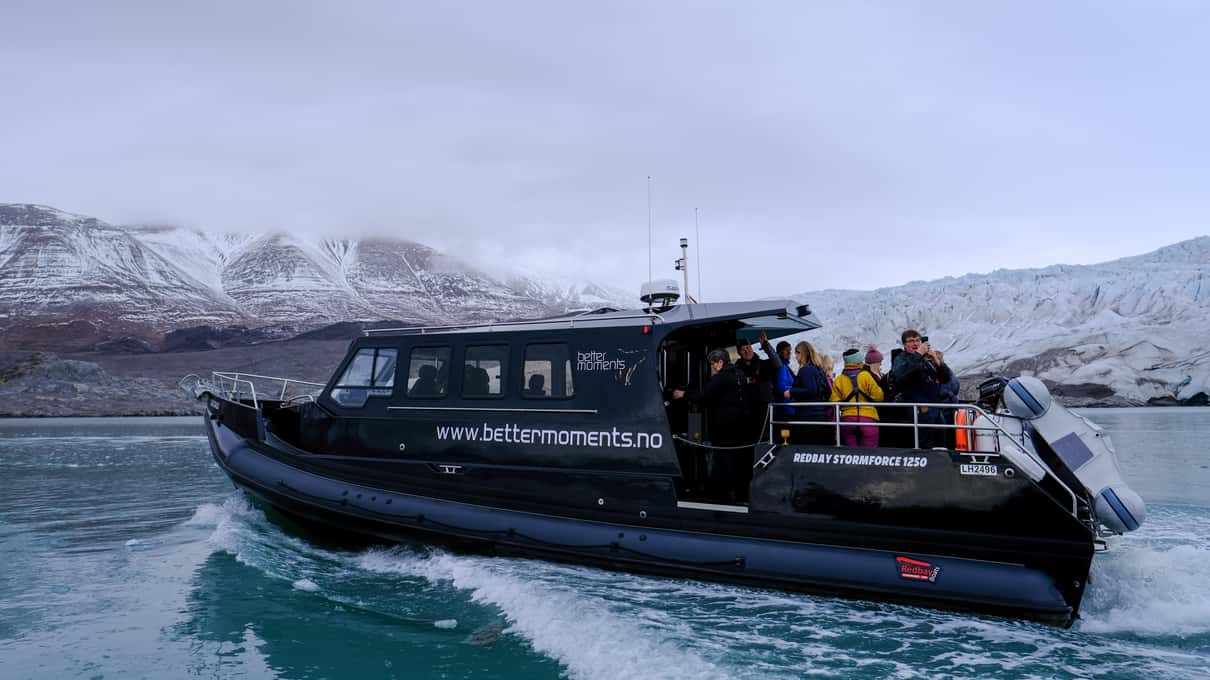 Skua Nature's small dark covered boat with guests standing on the stern deck