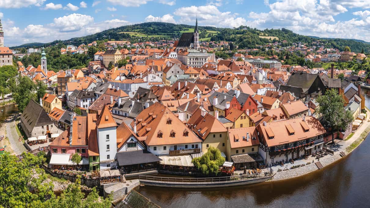 Aerial view of Český Krumlov with its red roofs and castle tower inside a tight bend of the Vltava