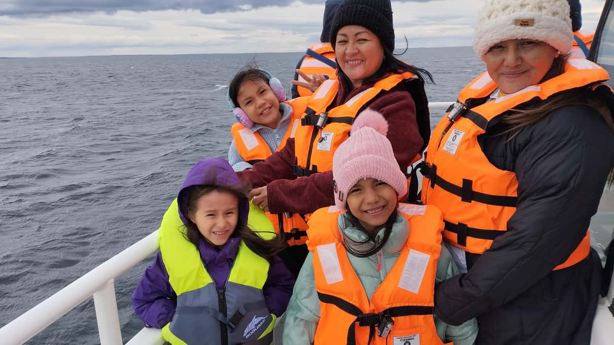 A family in orange life vests on deck crossing the Strait of Magellan on a penguin tour