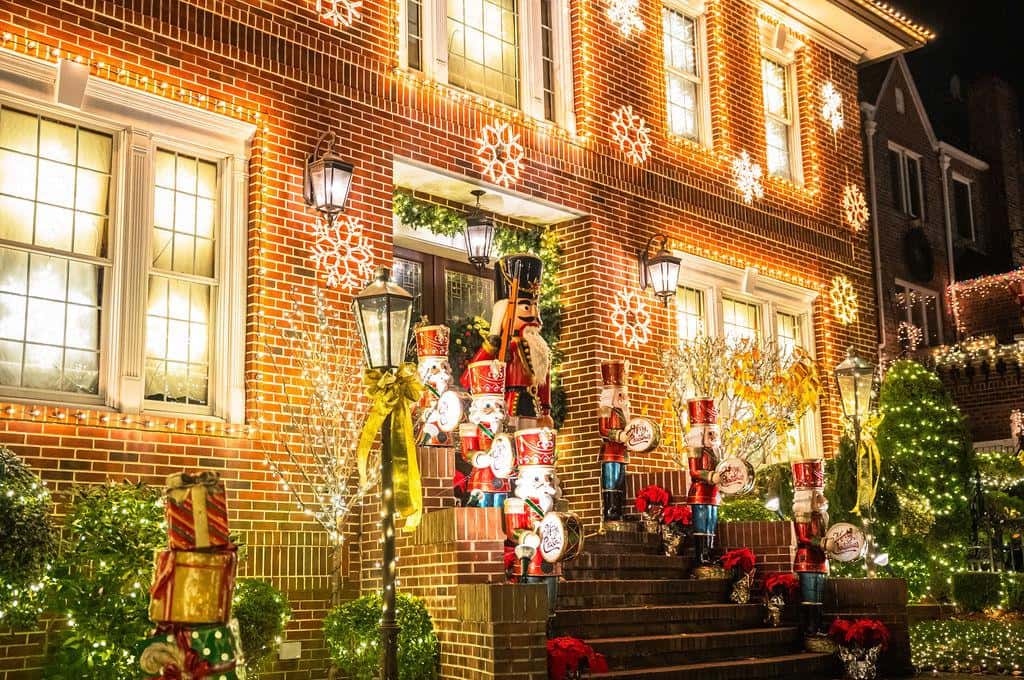 A brick house in Dyker Heights with nutcracker figures and strings of lights beside the front door