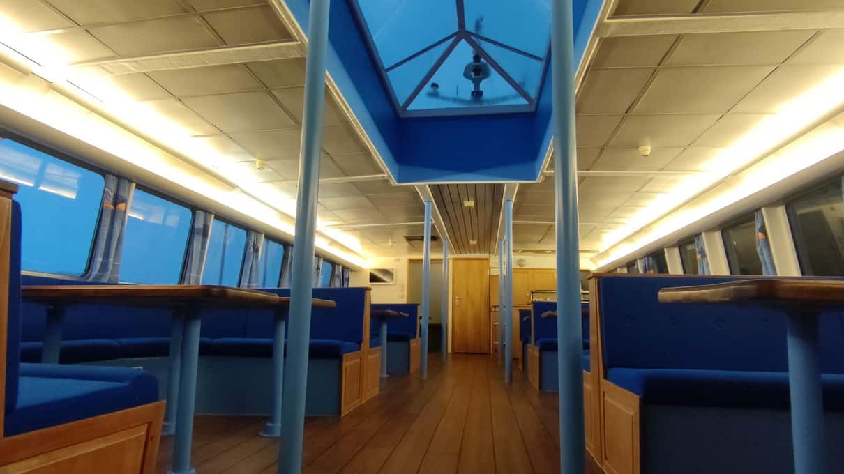 Indoor cabin with rows of blue seats and skylights in the roof on a Sea Trips boat