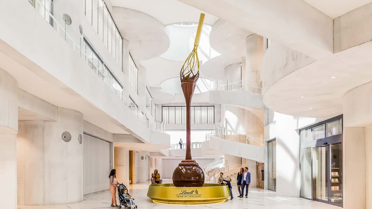 Giant chocolate fountain with a golden whisk rising in the white atrium of the Lindt Home of Chocolate