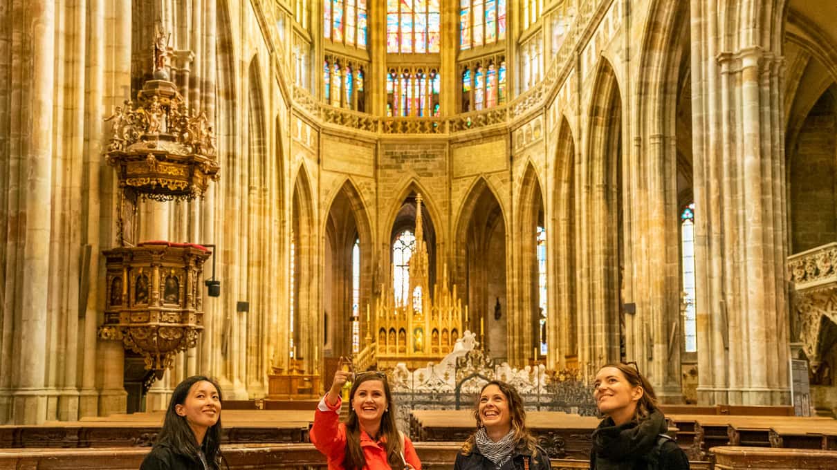 A guide speaking to a small group inside the Gothic nave of St. Vitus Cathedral at Prague Castle