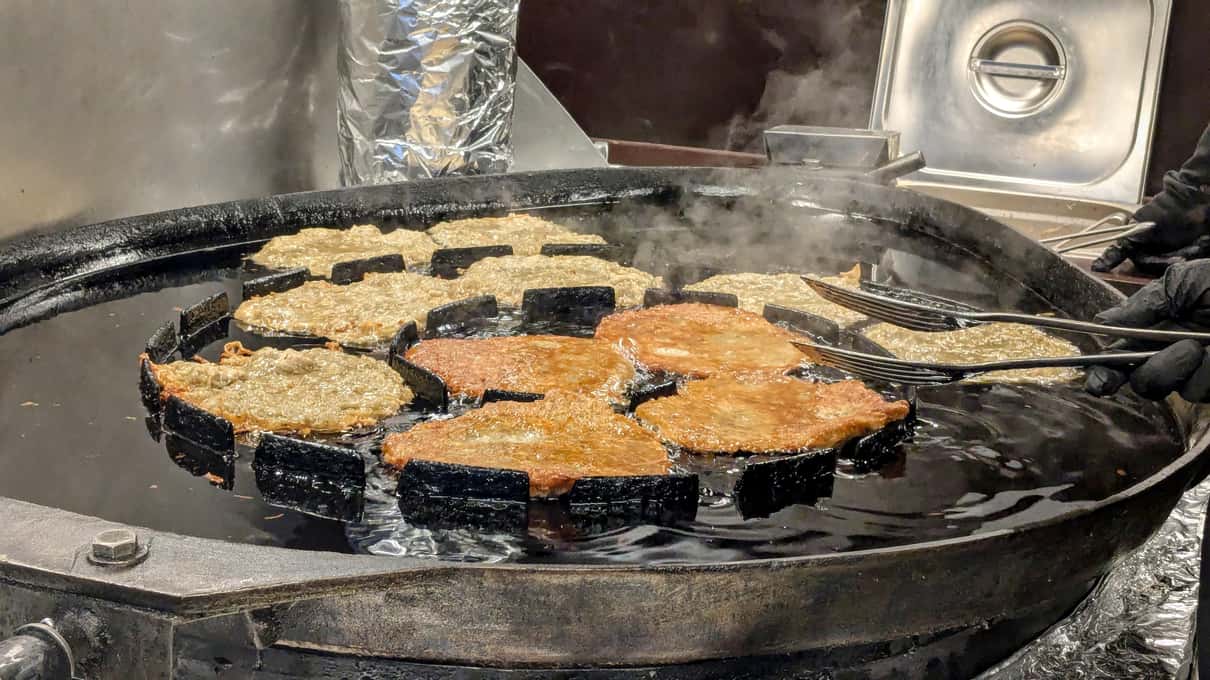 Golden potato pancakes frying in a large pan at a Christmas market stall in Vienna