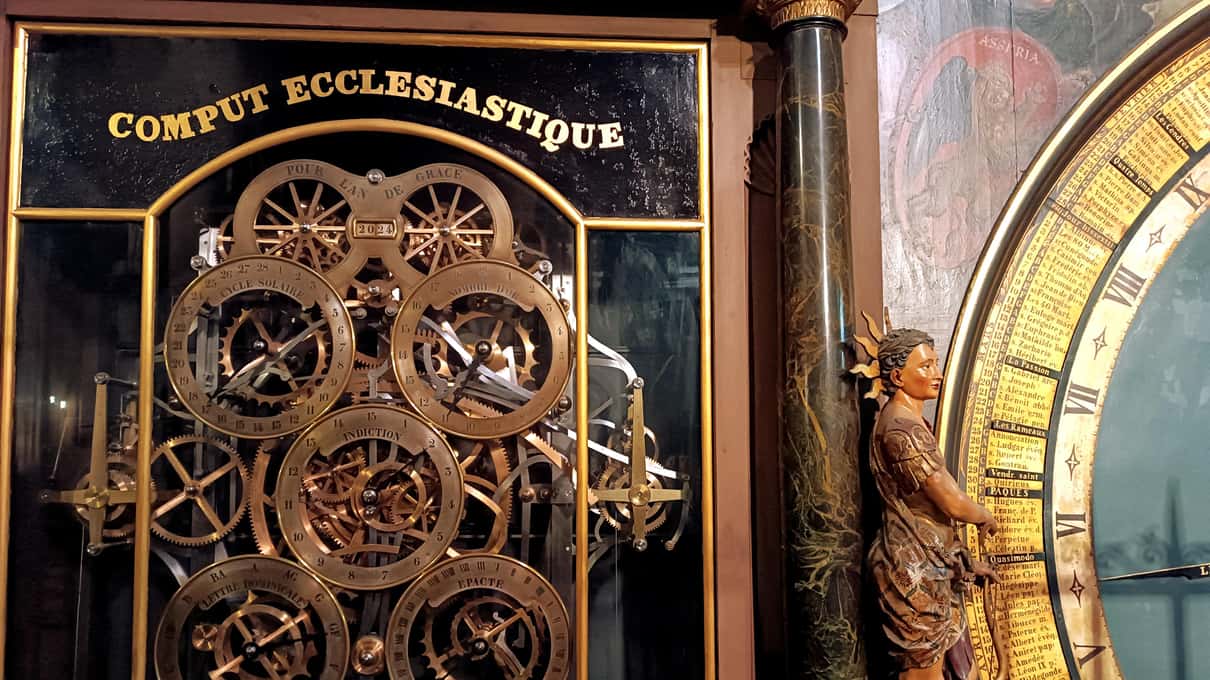 Detail of the astronomical clock in Strasbourg cathedral, gilded gears and dials under a panel reading Comput ecclésiastique