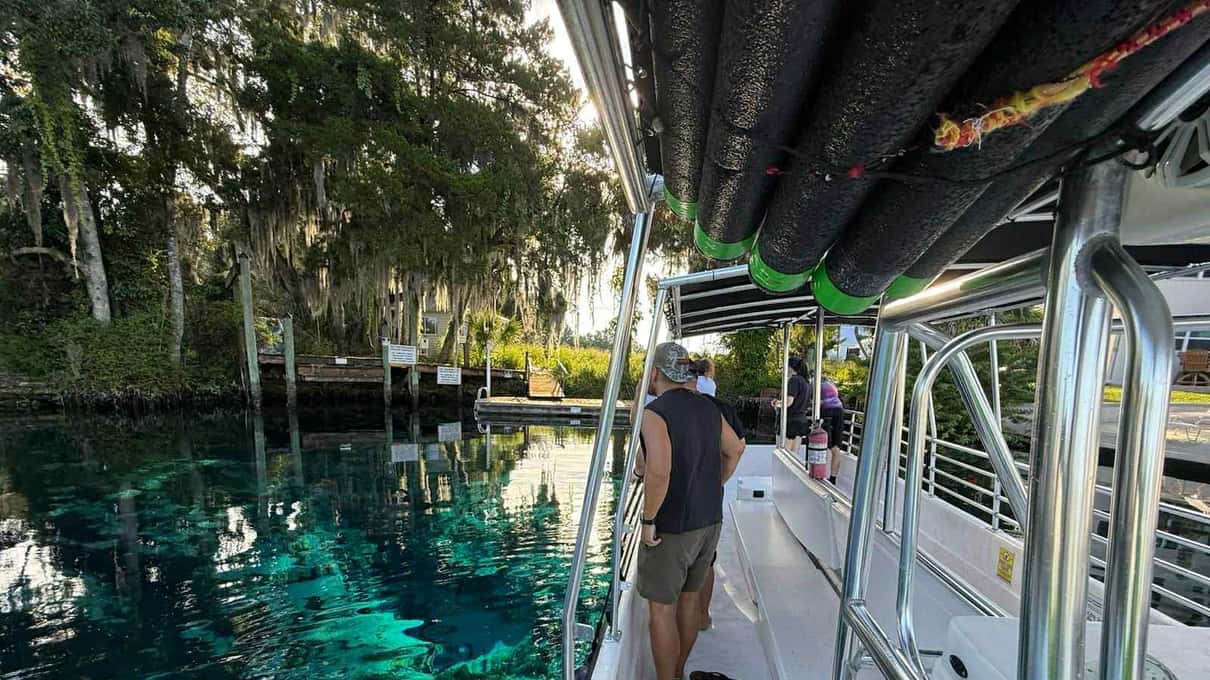 The deck of a manatee viewing boat over clear turquoise water lined with trees