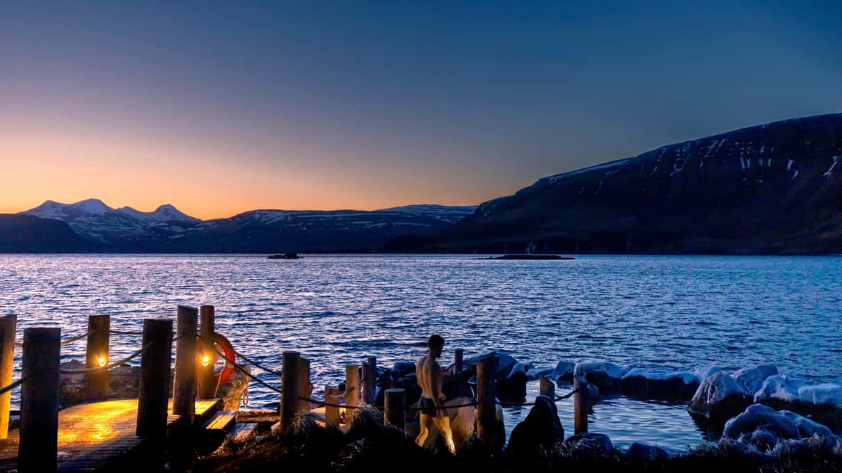 Bathers resting in the Hvammsvik hot pools at golden hour on the Hvalfjörður shore