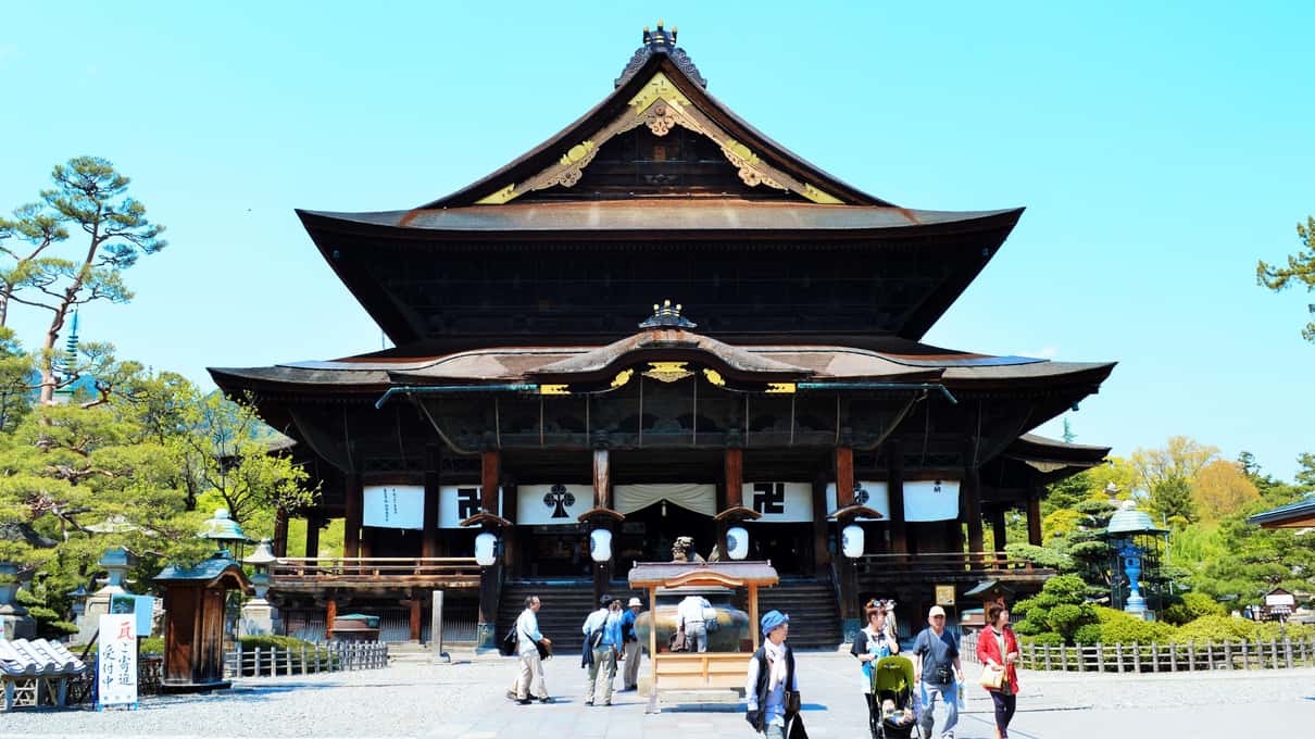 The large wooden main hall of Zenko-ji temple in Nagano under a clear blue sky