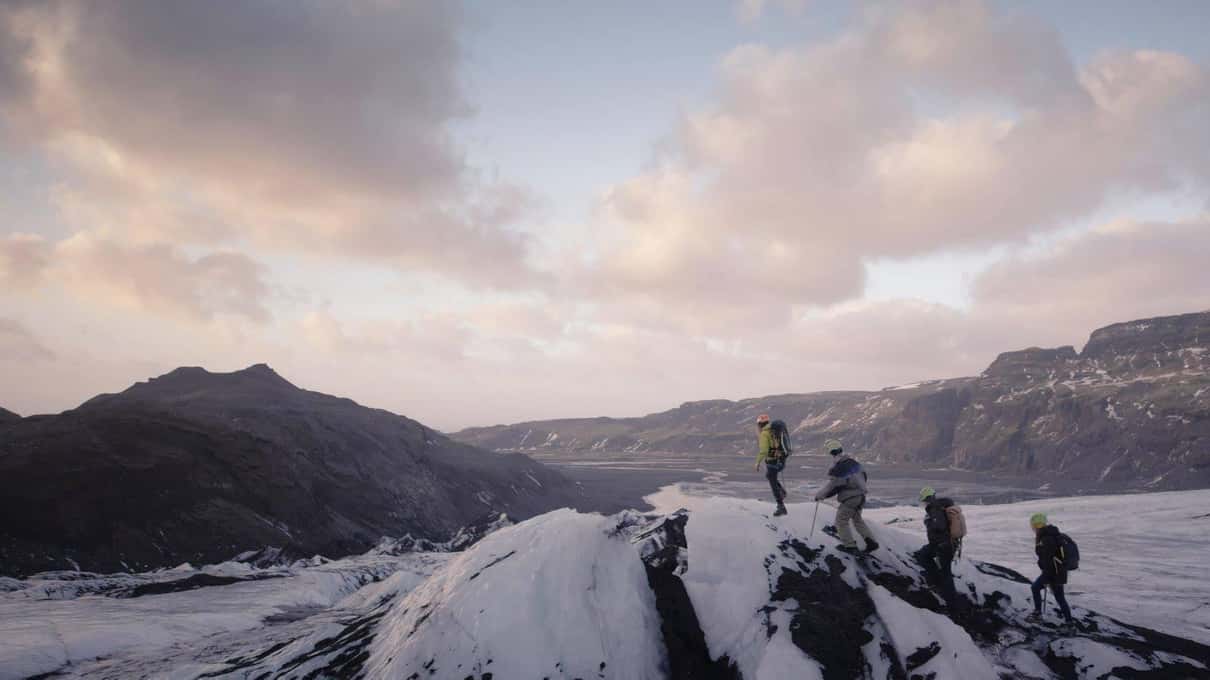 Two hikers standing on the glacier surface of Sólheimajökull in the low evening light