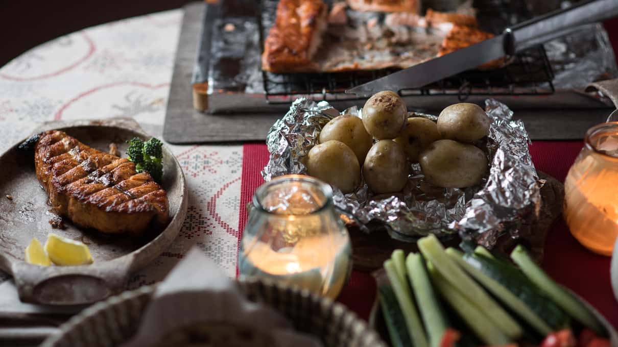 Smoked salmon with baked potatoes in foil on a cottage table by candlelight
