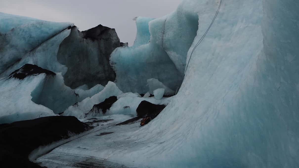 Ridges of blue and white ice on the surface of Sólheimajökull glacier under a grey sky