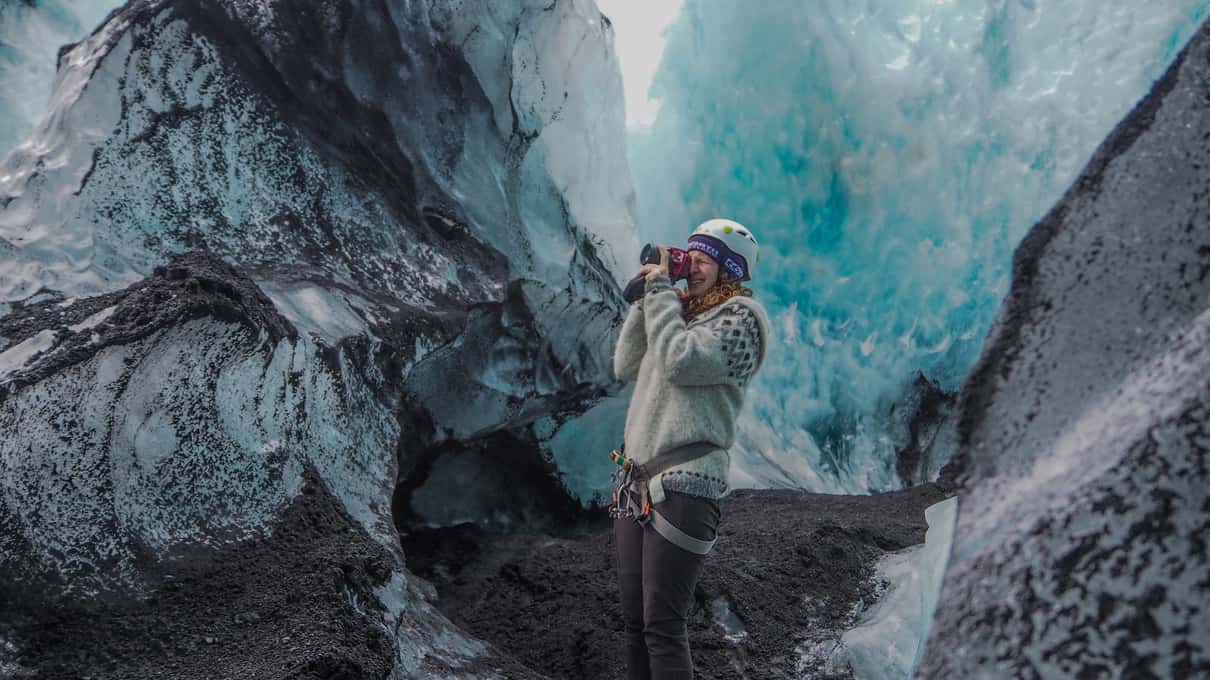 A climber kicking crampons into a blue ice face on the Sólheimajökull glacier