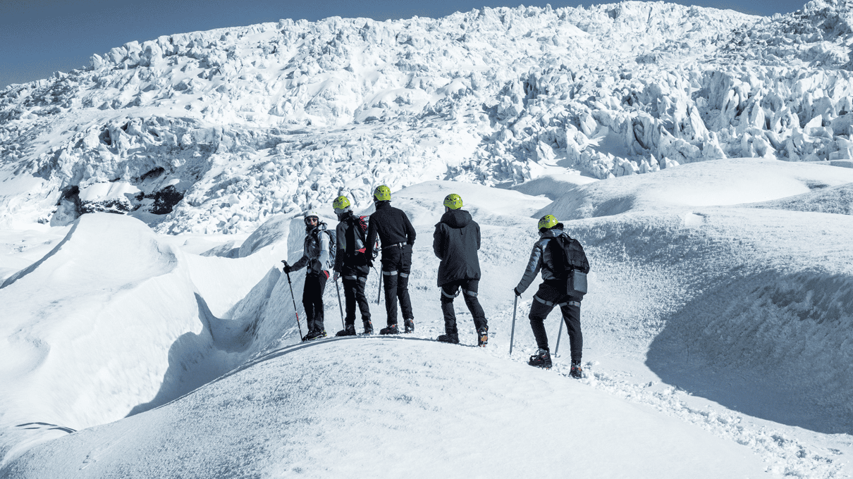 Roped line of hikers with ice axes climbing a snow-covered ridge high on Falljökull glacier in Skaftafell