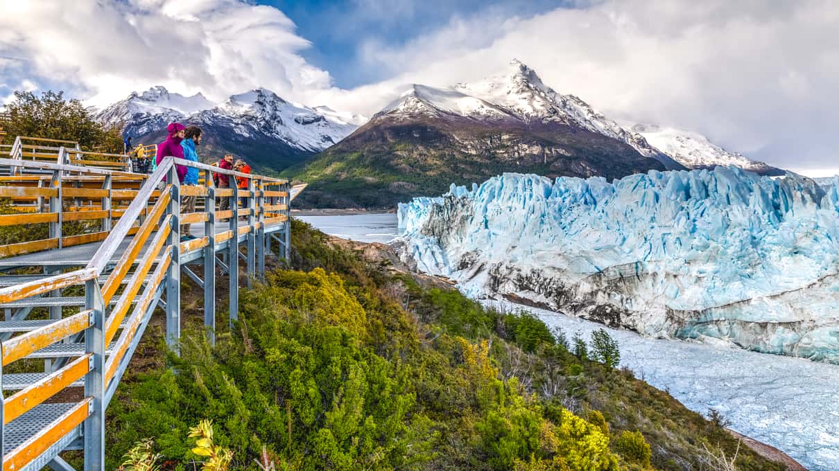 Visitors on the walkways looking across the water at the wide ice front of Perito Moreno Glacier