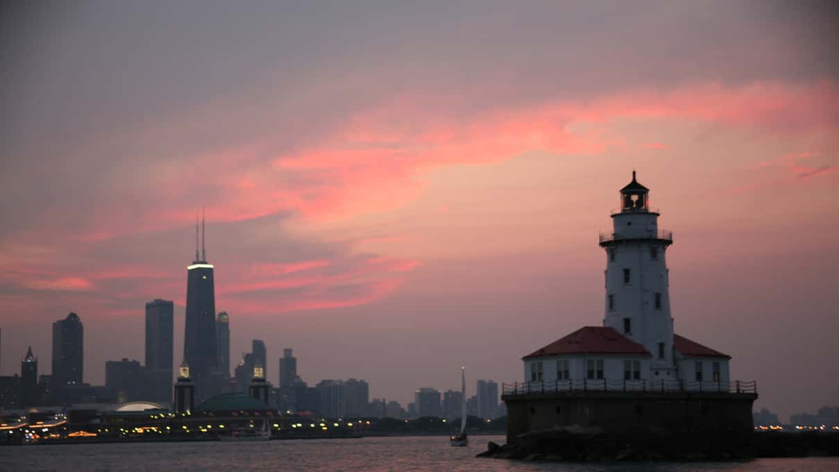 The Chicago skyline at dusk seen from Lake Michigan with a small lighthouse in the foreground