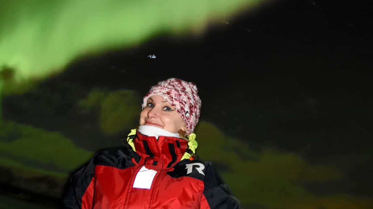 A woman in a knitted hat looking up at the night sky from the deck of an Elding boat