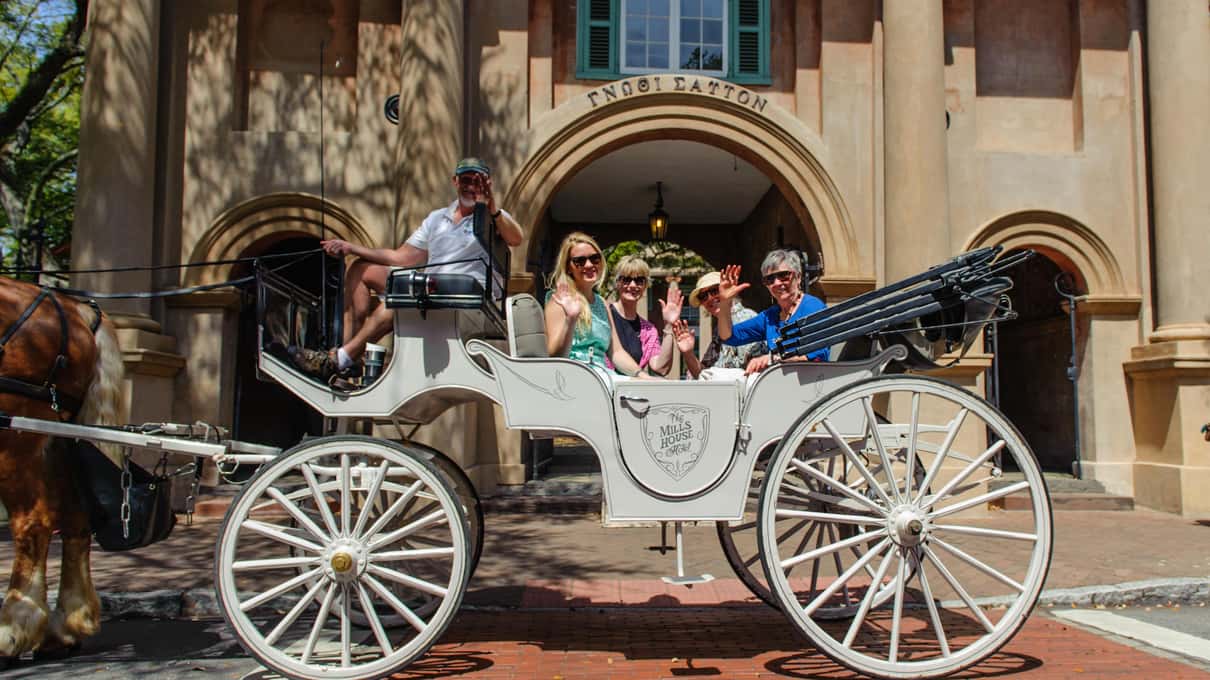 A family seated in a white private Palmetto carriage in front of an old arched building