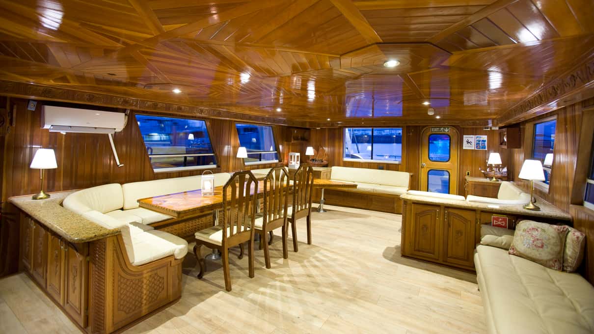 Wood-panelled salon with tables and warm lighting inside a Sea Trips yacht