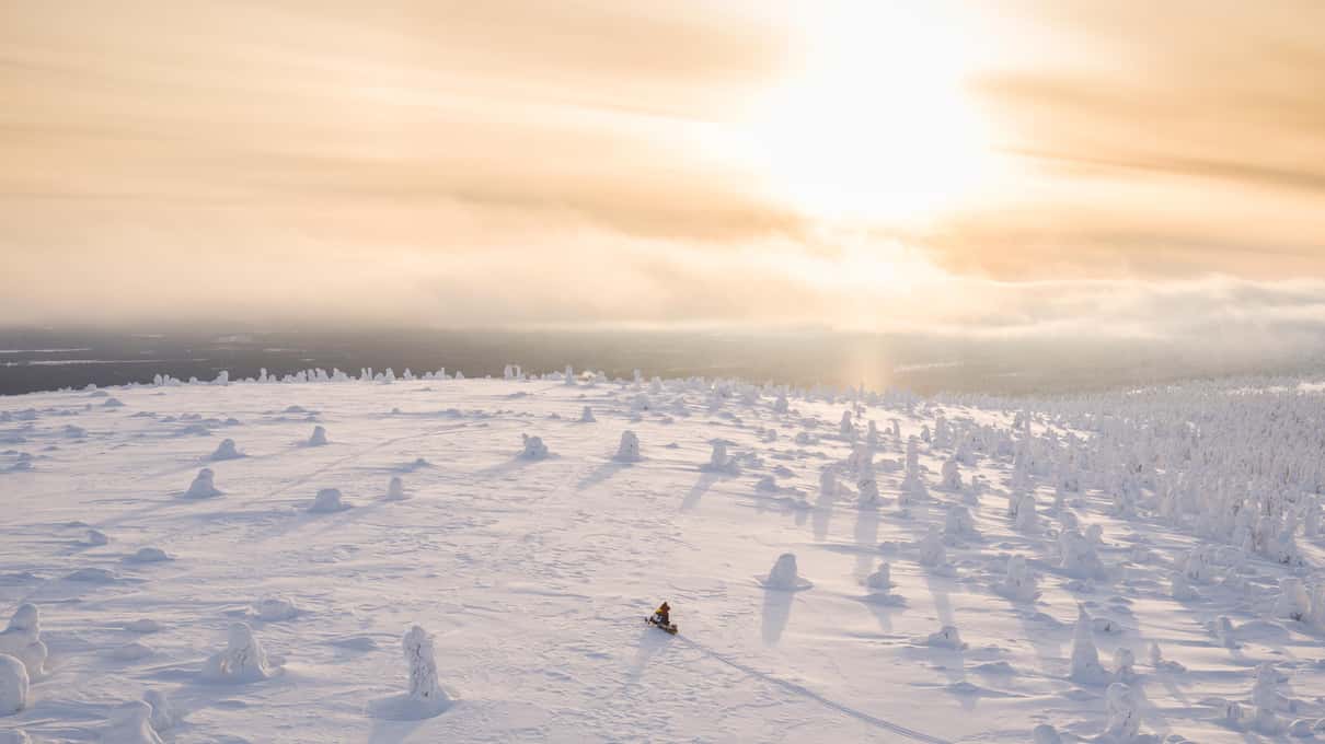 Low winter sun over a snow-covered frozen lake in Lapland on a clear cold day