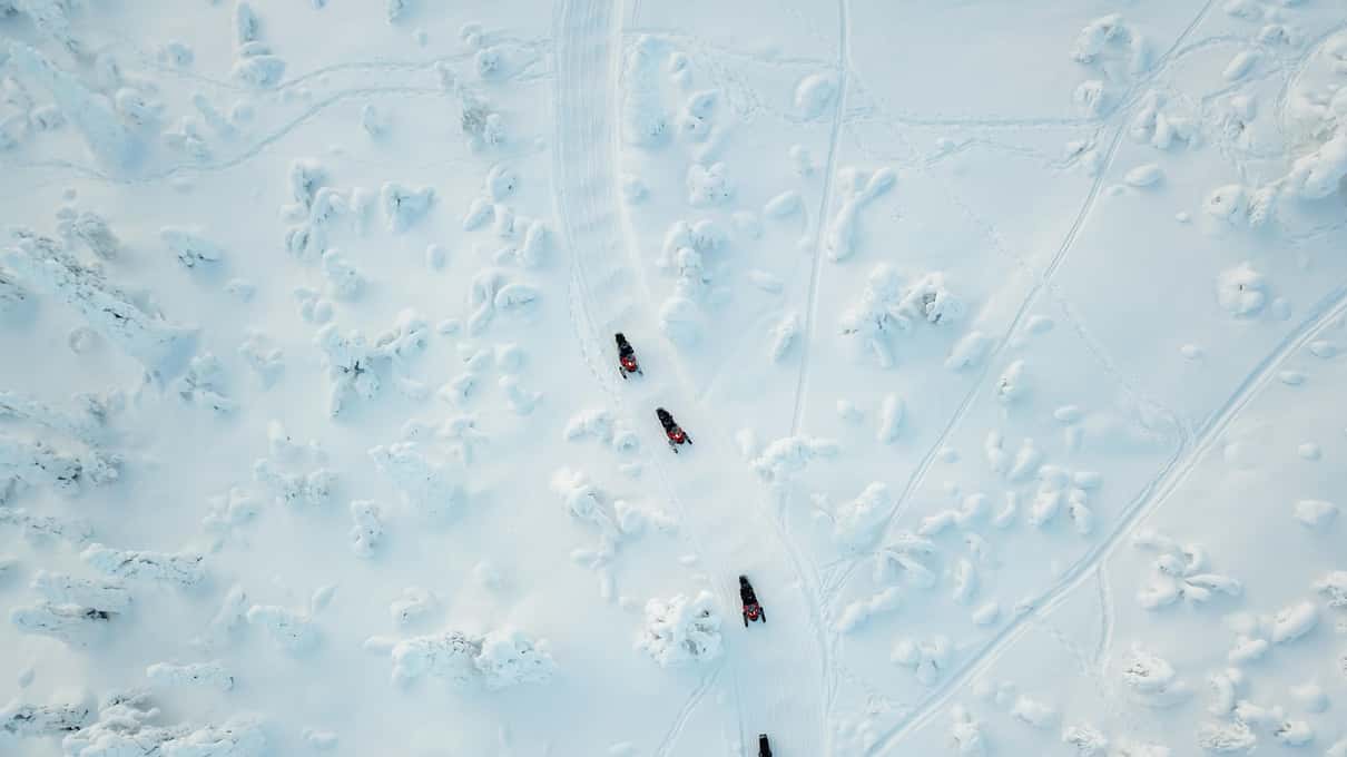 An aerial view of a few people fishing through holes on a wide frozen lake