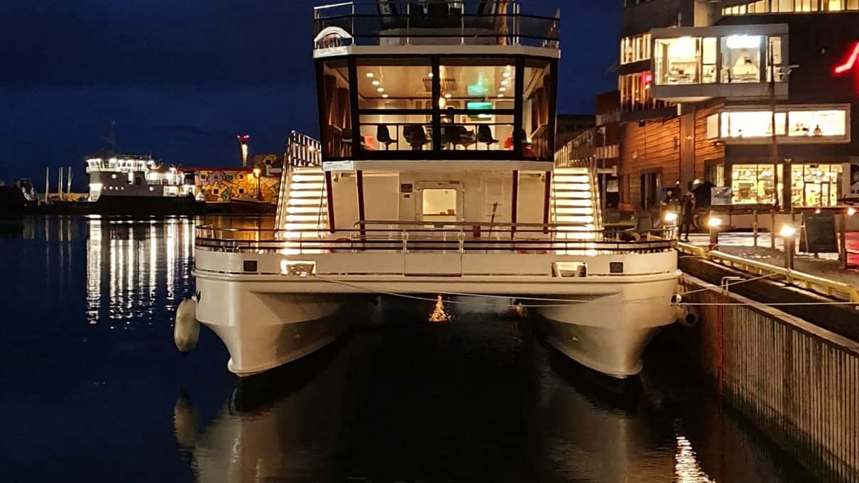 Brim Explorer's white boat moored at a lit quay in Svolvær harbor at night