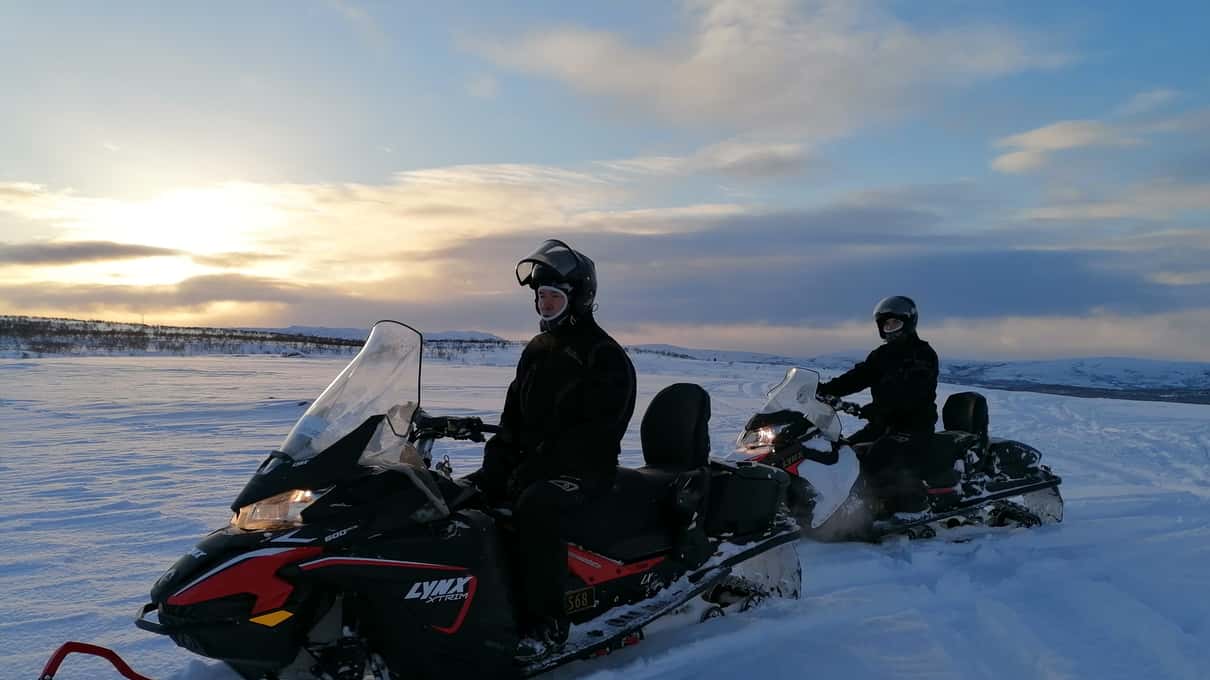 A snowmobile rider on the open Finnmarksvidda plateau against the low late winter sun