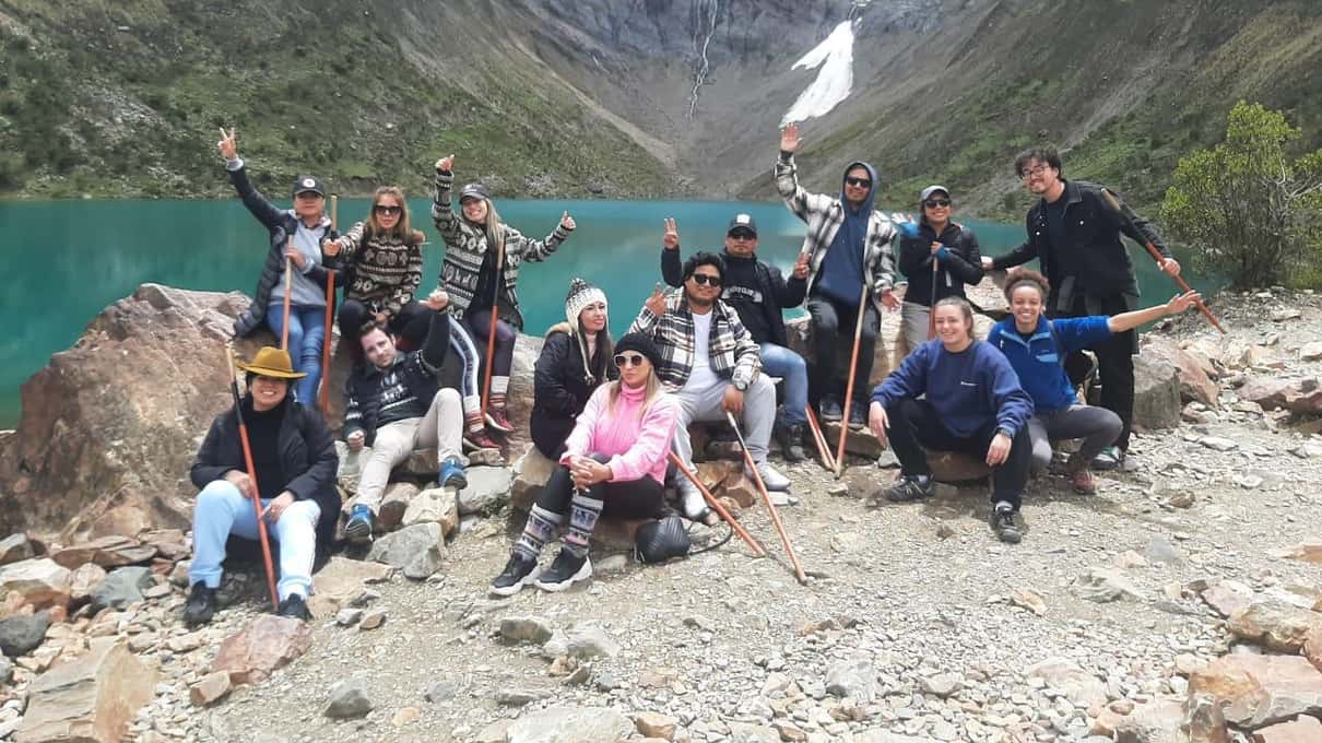 Hikers sitting on large boulders above the lake to catch their breath at high altitude