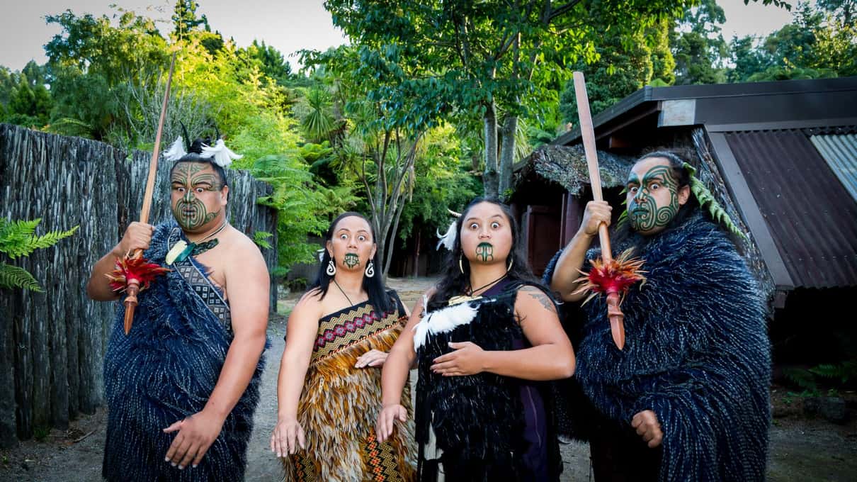 Mitai hosts in feather cloaks and traditional dress waiting to welcome guests at the village gate