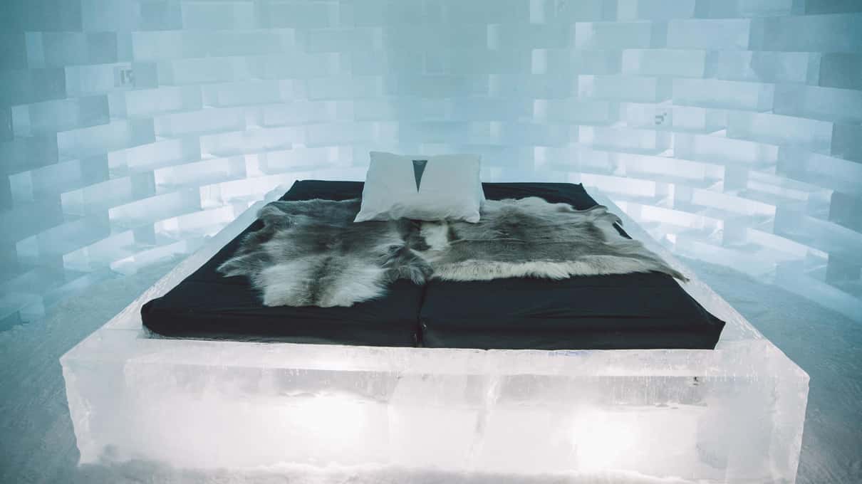 A bed on a block of ice covered with reindeer hides in an Icehotel room