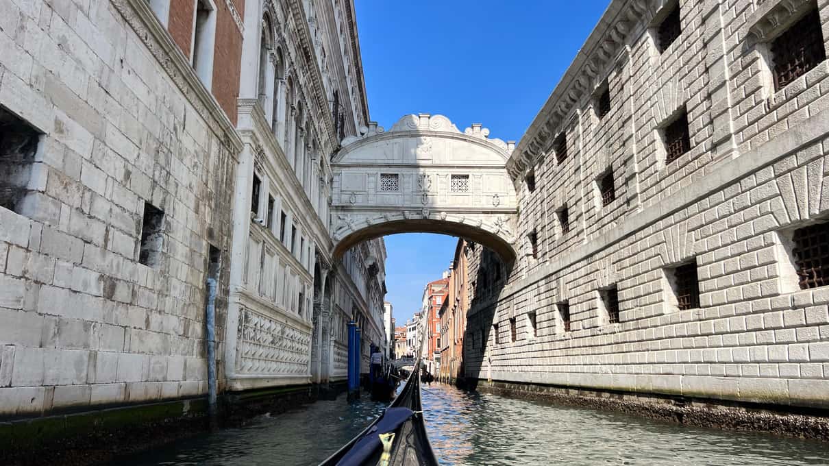 El Puente de los Suspiros de piedra blanca sobre el canal entre el Palacio Ducal y las antiguas prisiones, con cielo azul