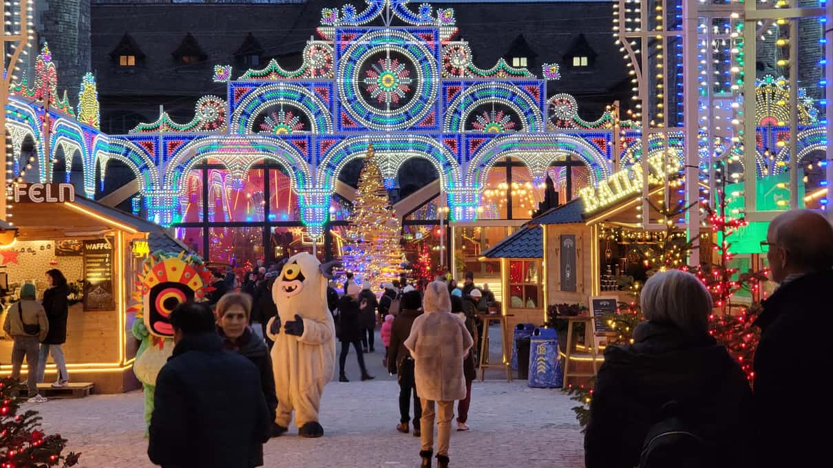 Arches of Christmas lights in the Landesmuseum courtyard in Zurich, with visitors and characters in polar-bear costumes
