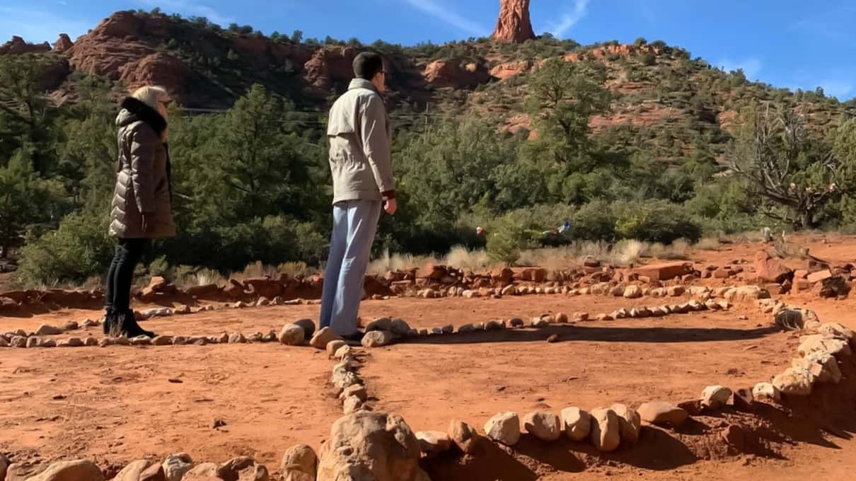 A jeep parked beside red rock formations at a Sedona vortex site with juniper trees in the foreground