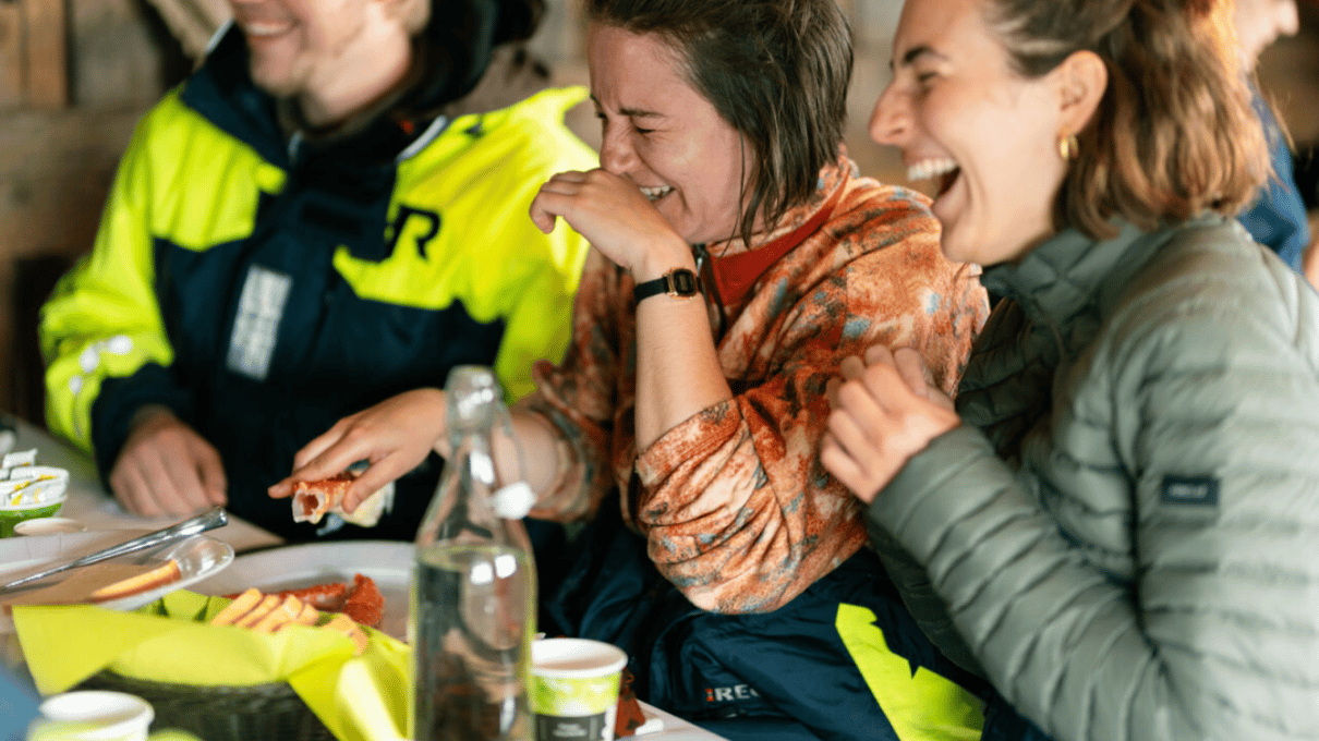 Guests laughing together around the table while they eat the king crab meal after the safari