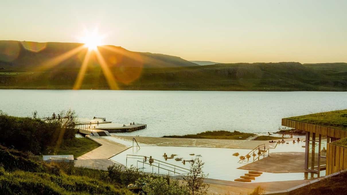 The Vök Baths pools floating on Lake Urriðavatn with the low sun shining over the far shore