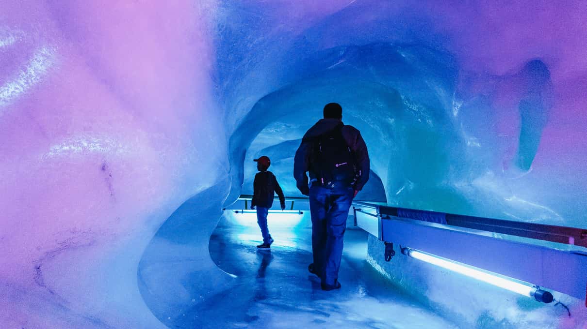 Visitors walking through the blue ice tunnel of the glacier cave on Titlis