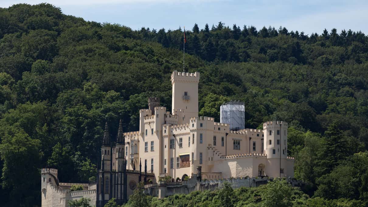 A castle on a wooded slope above the Rhine near Koblenz seen from the river