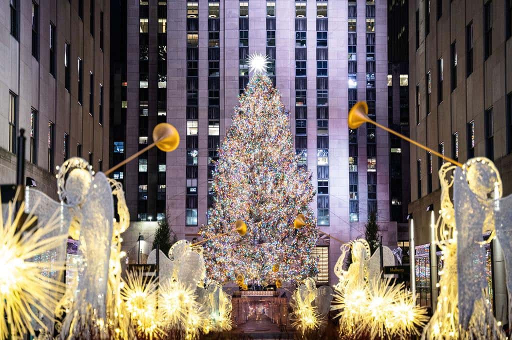 The Rockefeller Center Christmas tree lit up between the plaza's trumpeting angel statues