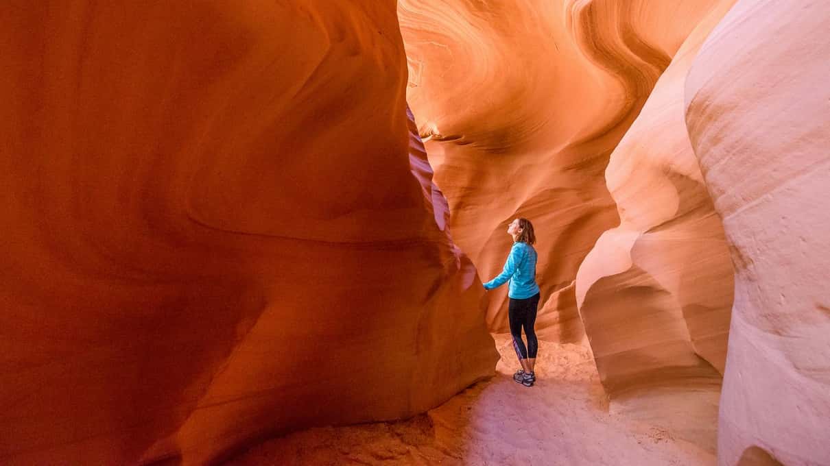 A small figure standing in a wide orange section of Antelope Canyon X