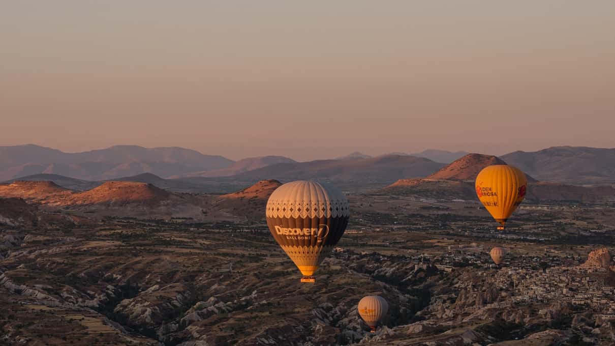 Balony wznoszące się o wschodzie słońca nad dolinami Göreme w Kapadocji