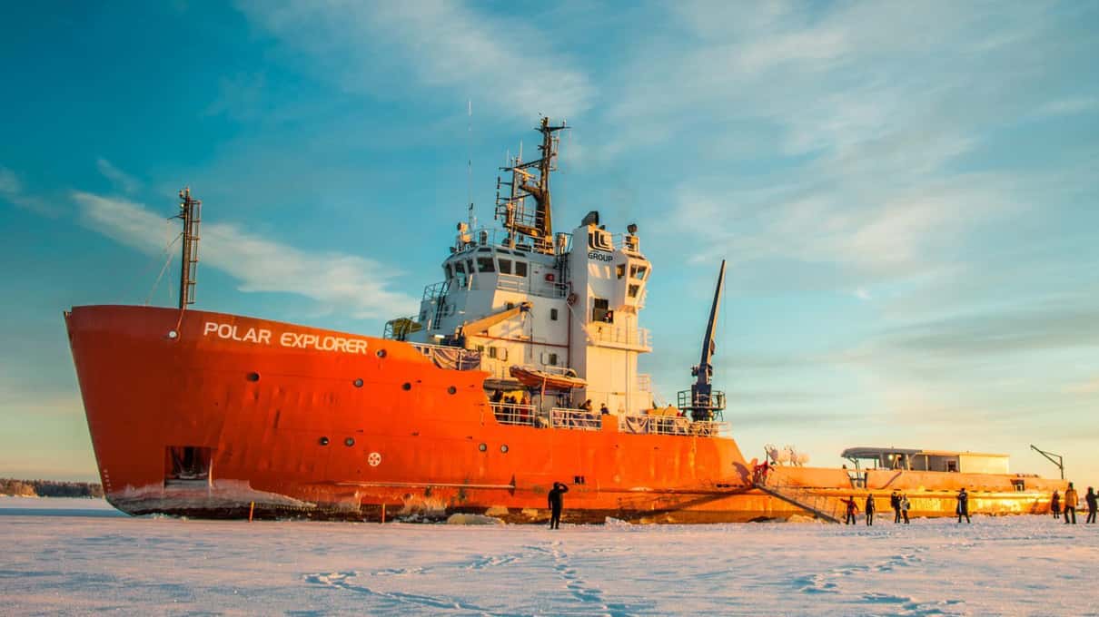 The red-hulled Polar Explorer icebreaker standing in the frozen sea ice at sunset