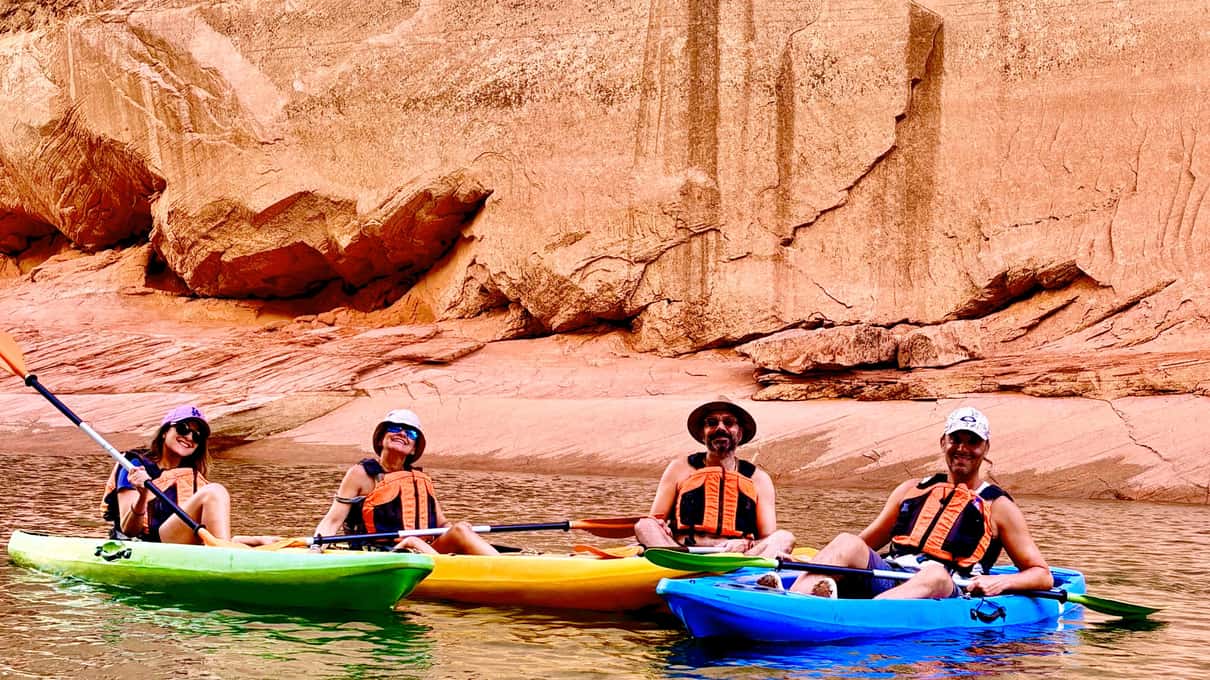 Colorful kayaks drawn up in a narrow water canyon between smooth sandstone walls on Lake Powell