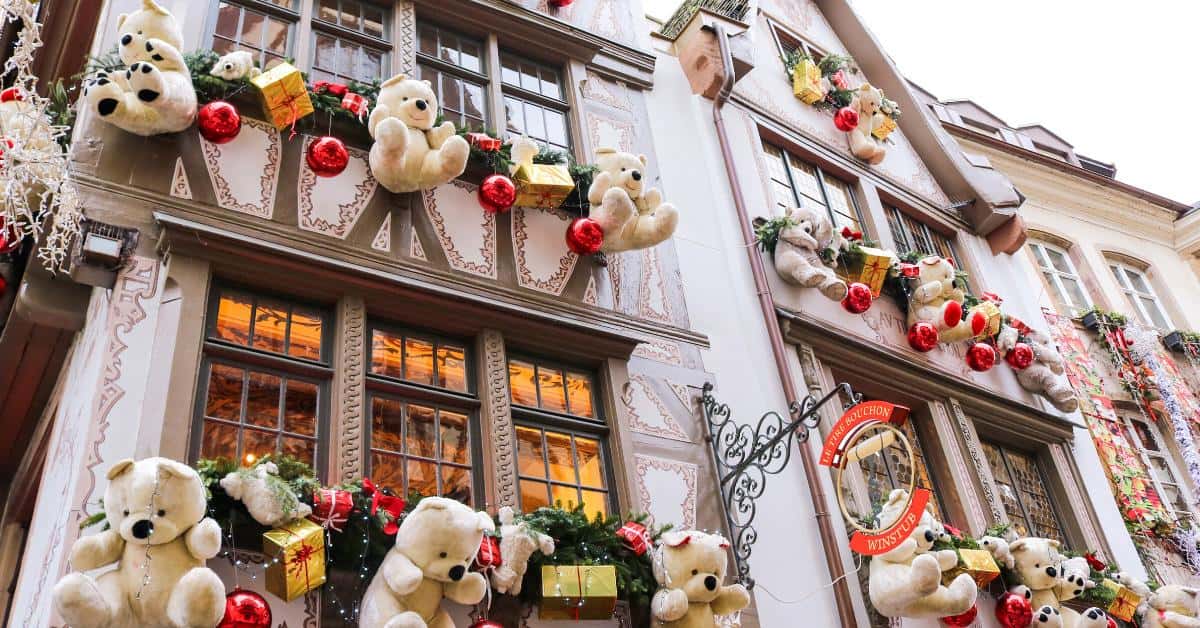 A building facade above a shop decorated with dozens of teddy bears, wrapped gift boxes and green garlands