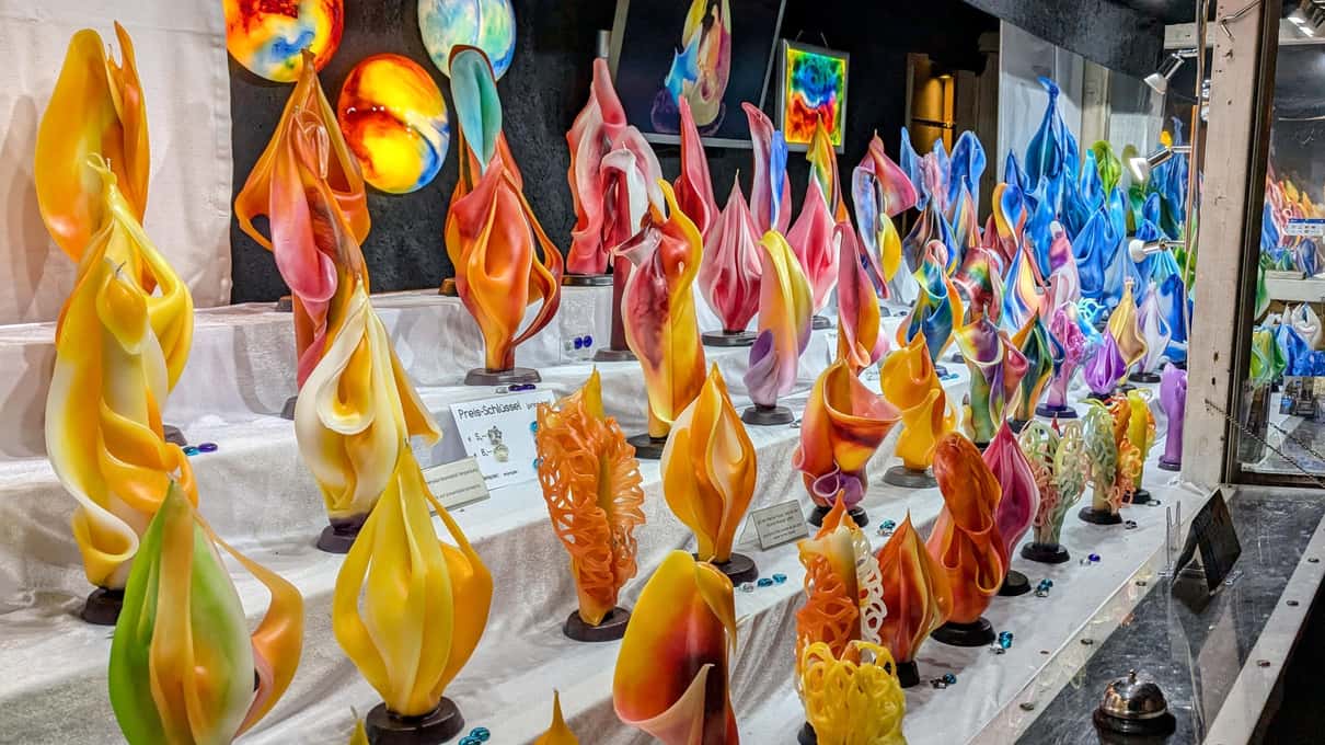 Rows of colorful blown-glass Christmas ornaments hanging and laid out on a wooden market stall in Vienna