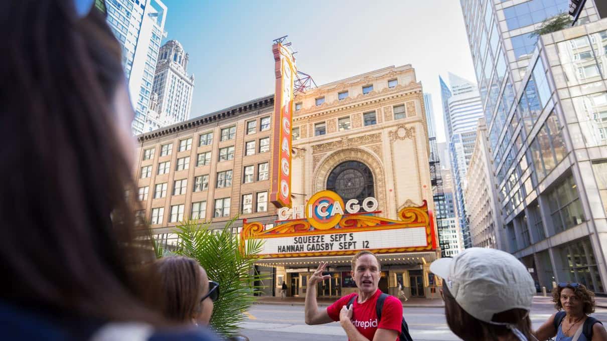 State Streetにある赤いChicago Theatreの看板の前で、グループに話しかけるガイド