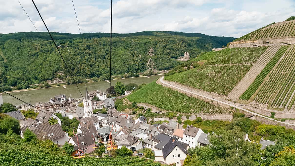 Open cable car cabins gliding above vineyard terraces and the village of Assmannshausen on the Rhine